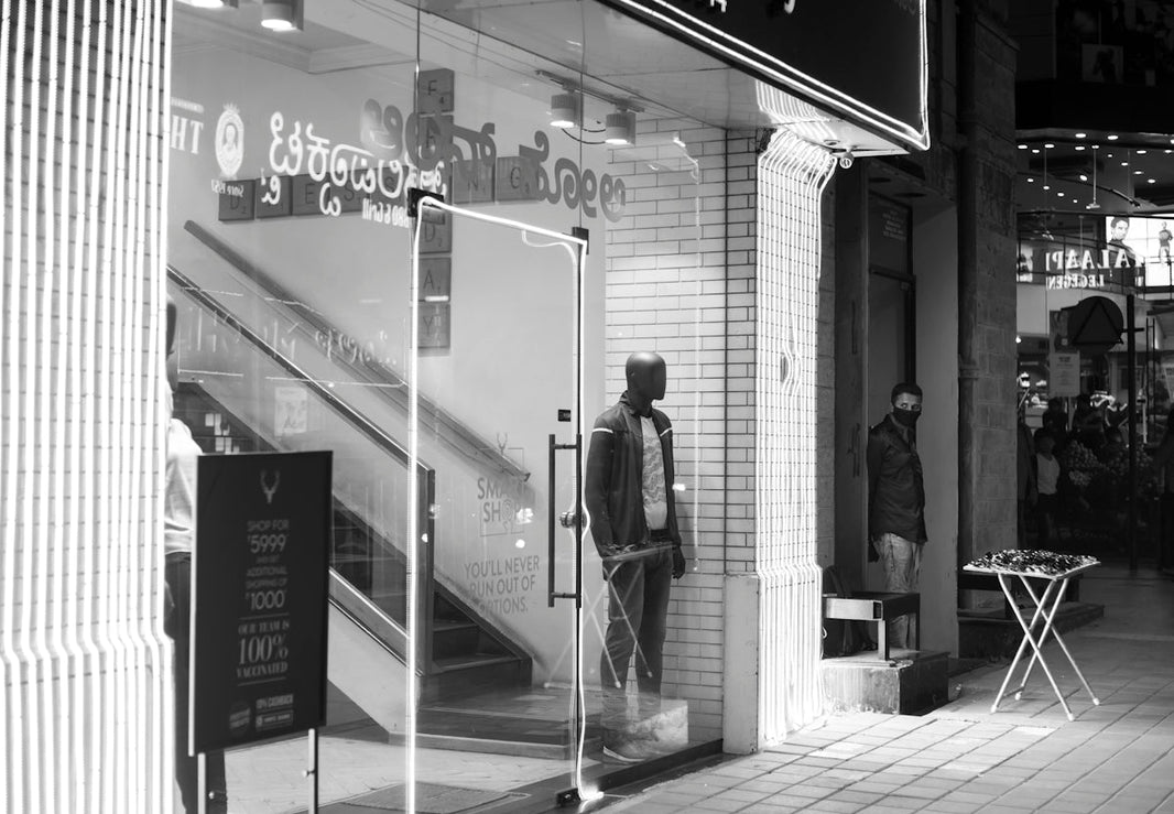 a black and white photo of a man standing in front of a store