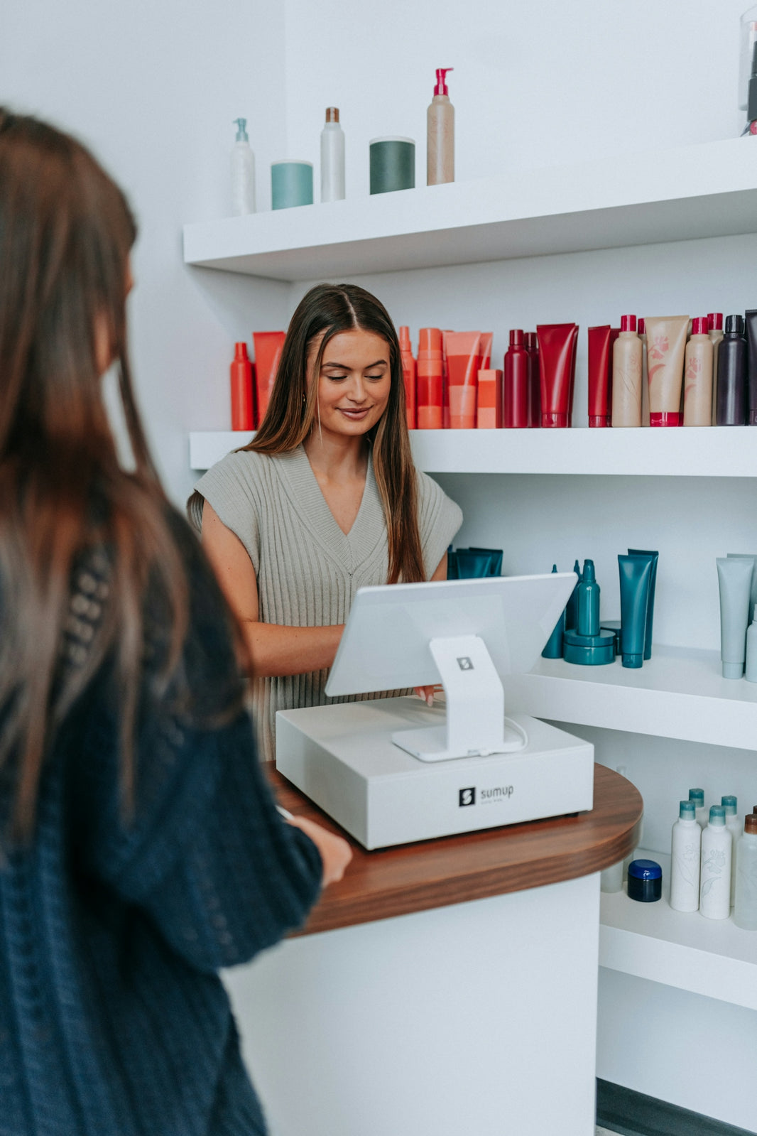 A hairstylist checks out a customer at the register