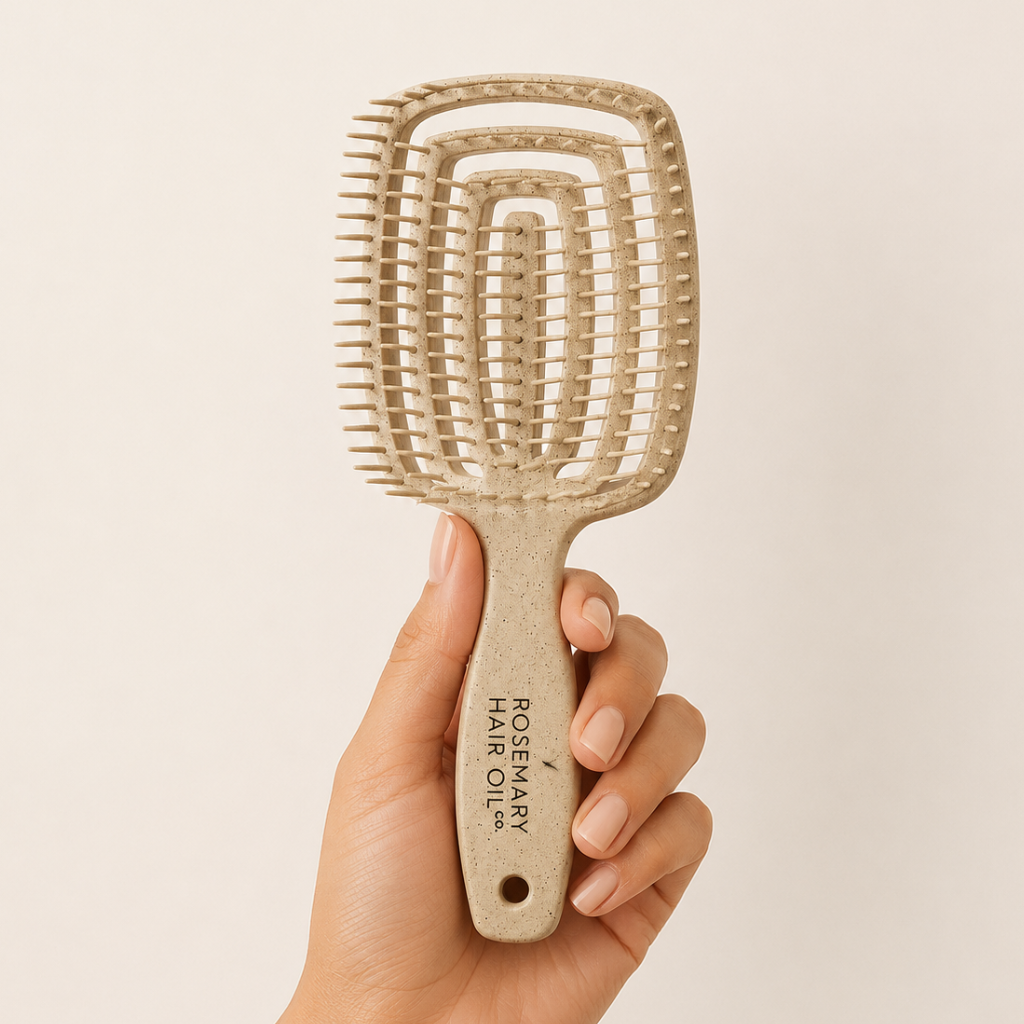 Hand holding a beige hairbrush with 'Rosemary Hair Oil Co.' branding on a beige background, Beige hairbrush with 'Rosemary Hair Oil Co.' branding on a beige background, detangle brush, tangle teaser, flexi brush