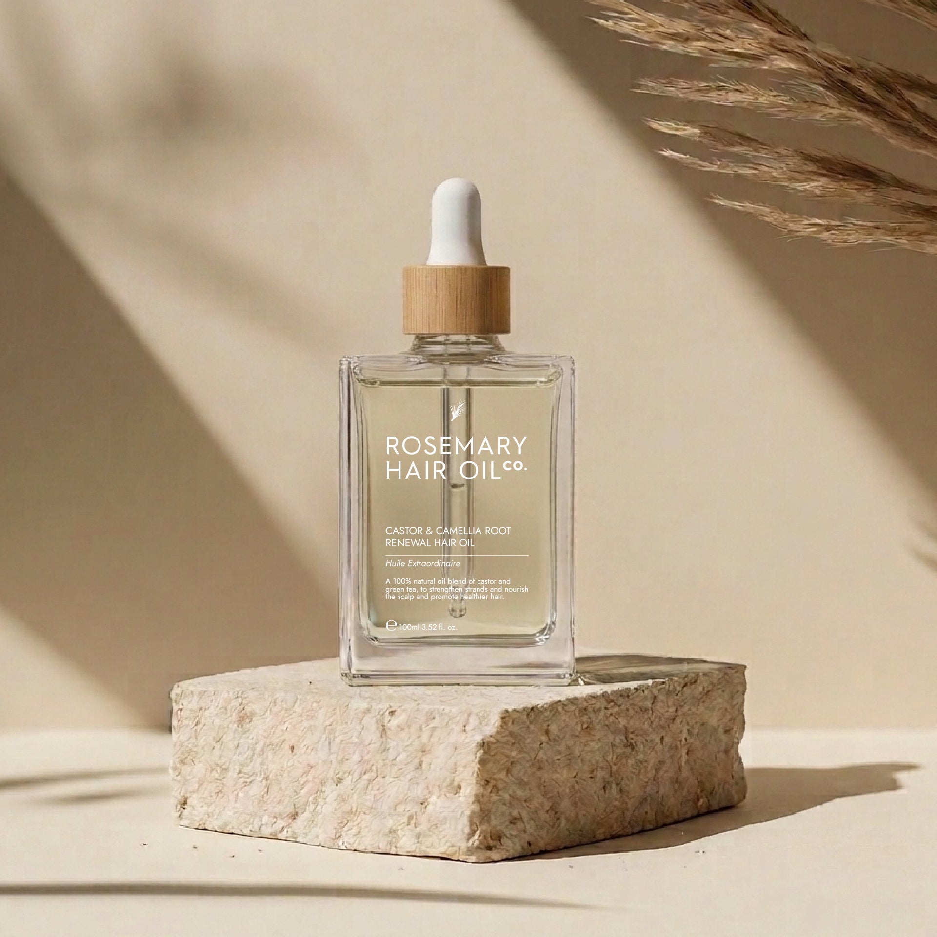 Rosemary Hair Oil Co. bottle on a stone platform with a neutral background. Rosemary hair oil, castor oil, camellia oil, apricot oil, hair growth, healthier, fuller-looking hair, stimulate, regrowth, hair thinning, natural, 100ml